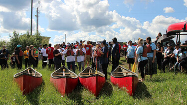 group of people outside in a field with 4 canoes