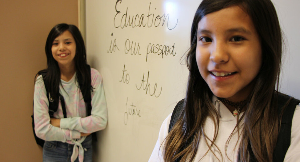 students standing in front of whiteboard that says "Education is our passport to the future"
